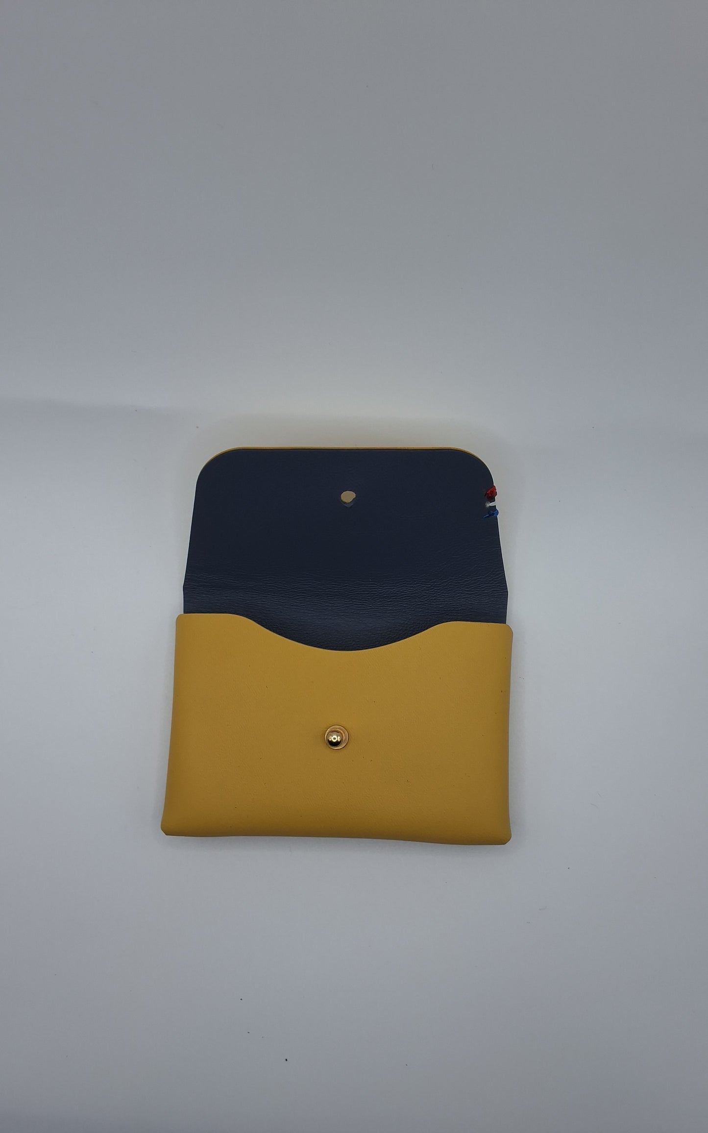 le porte carte colette est présenté ouvert sur un fond blanc. il est jaune à l'extérieur et bleu à l'intérieur
