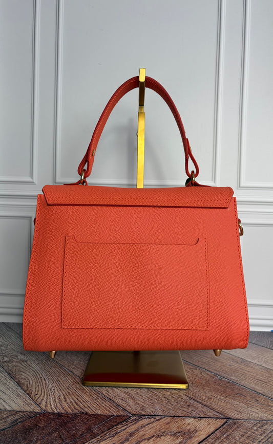 Le sac Simone en cuir corail est présenté sur un support de sac en laiton de dos. 