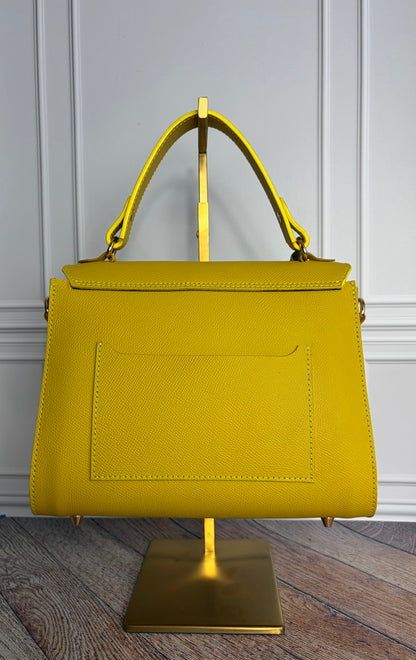 Le sac Simone en cuir jaune est présenté sur un support de sac en laiton de dos. 
