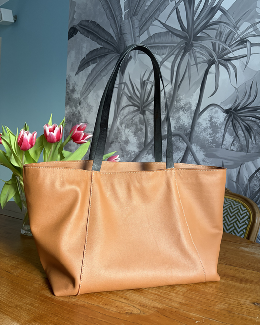 photo du sac cabas Albane en cuir marron au tannage végétal et anses en cuir noir posé sur une table en bois avec un bouquet de tulipe derrière. 
