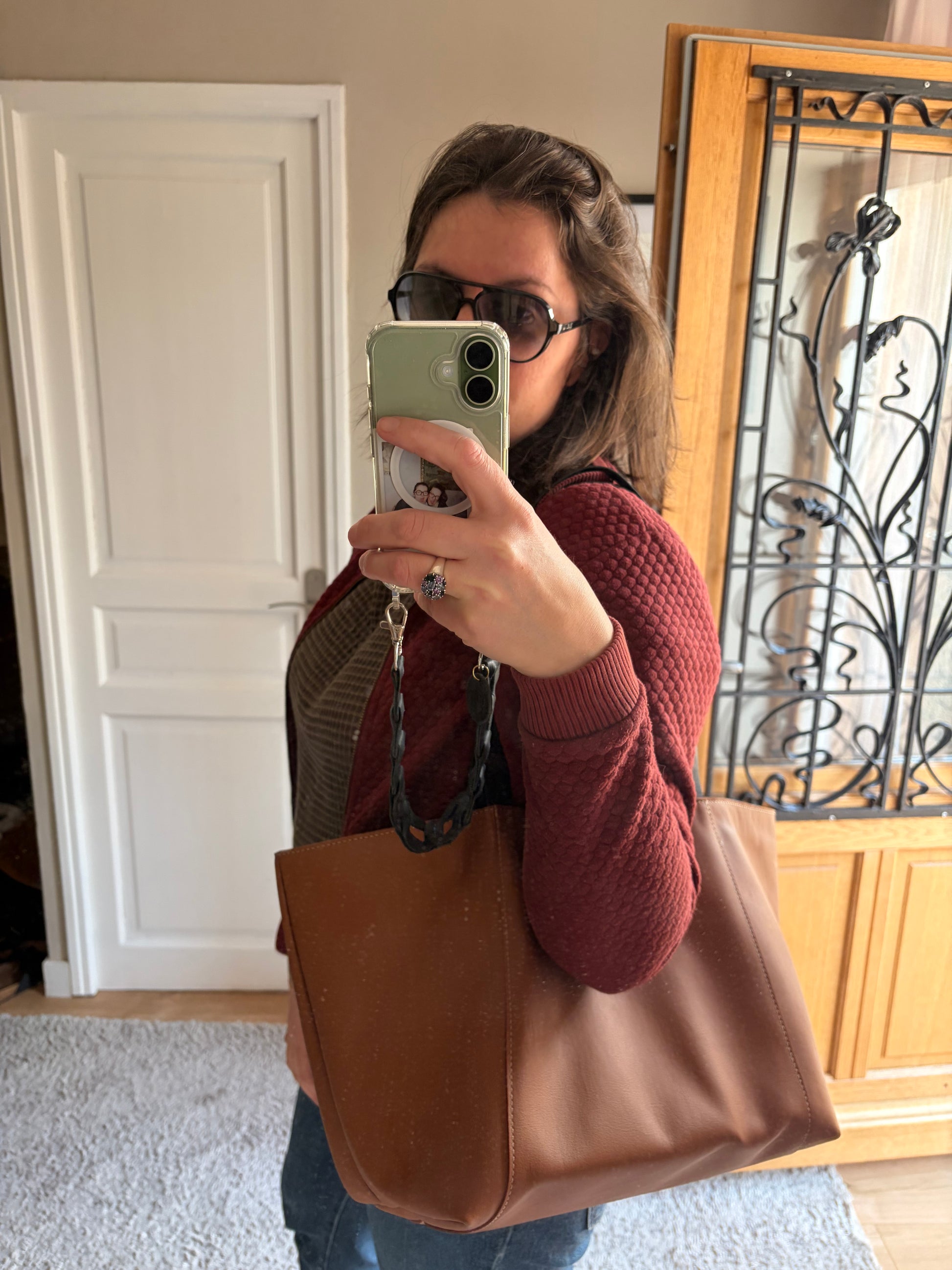 sac cabas en cuir porté à l'épaule dans une entrée de maison lumineuse et classique