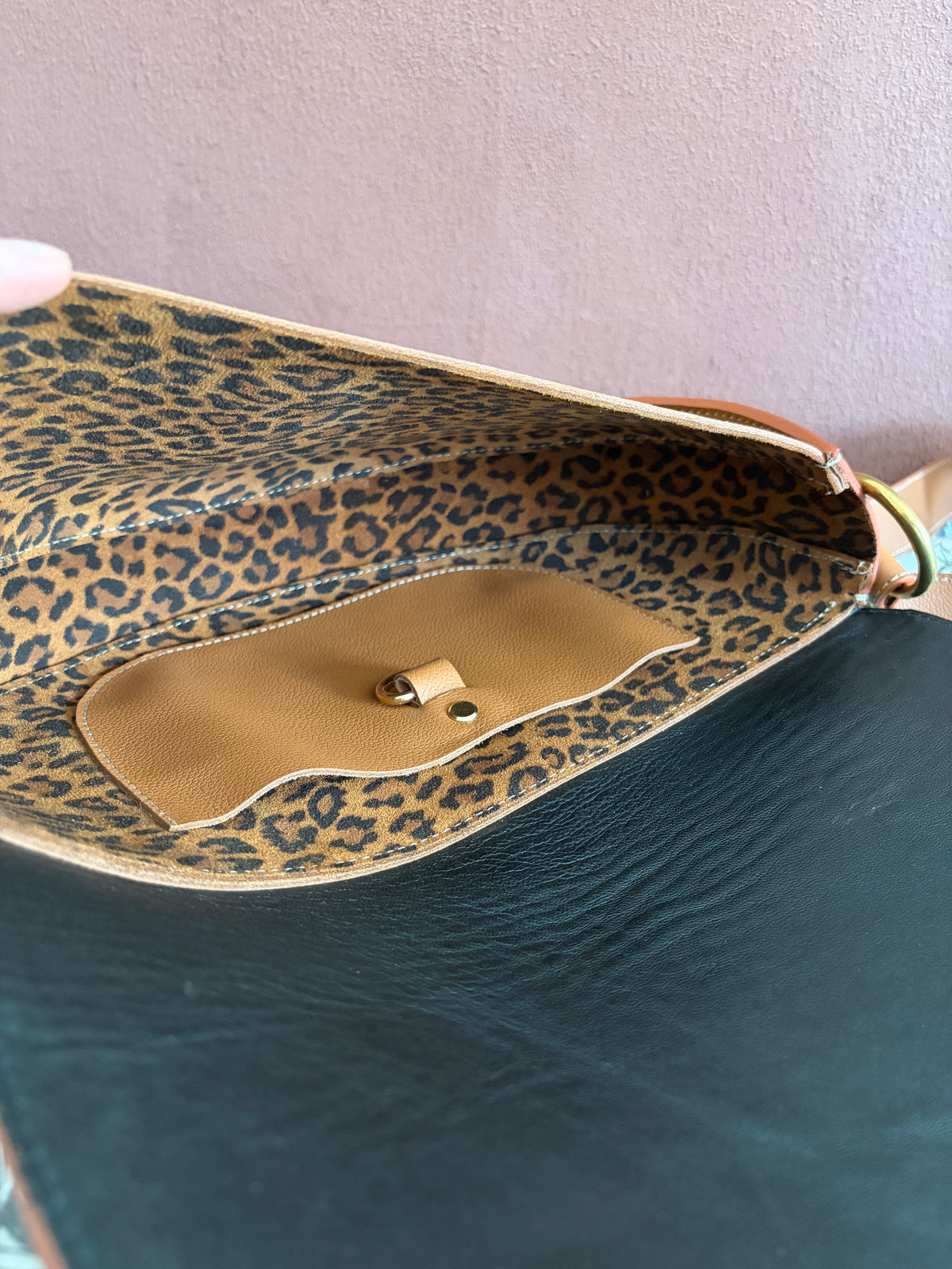 la photo présente l'intérieur du sac demi lune en cuir marron. le cuir intérieur est en cuir au motif léopard avec une poche plaquée en cuir marron