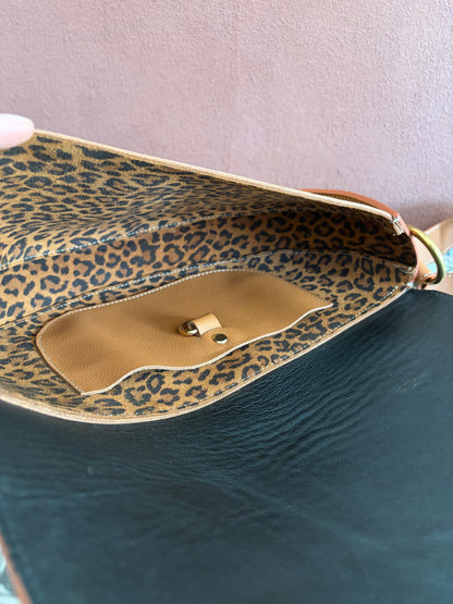 la photo présente l'intérieur du sac demi lune en cuir marron. le cuir intérieur est en cuir au motif léopard avec une poche plaquée en cuir marron