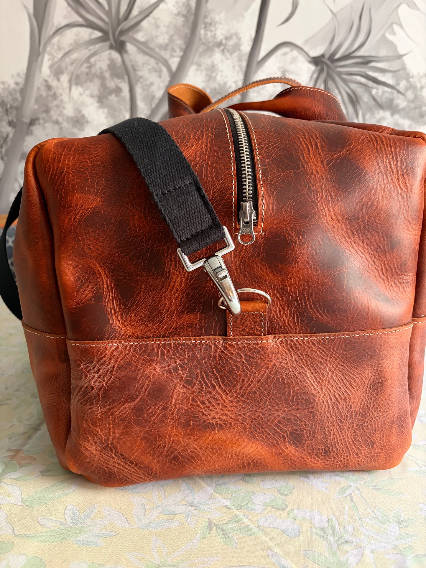 sac de voyage Marius en cuir marron wax vu de côté pour montrerle détail de la sangle et du mousqueton en acier