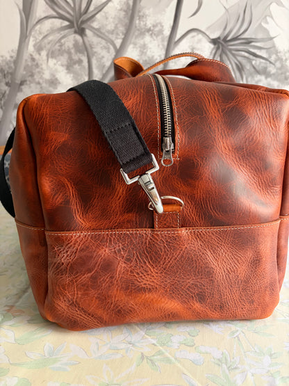 sac de voyage Marius en cuir marron wax vu de côté pour montrerle détail de la sangle et du mousqueton en acier