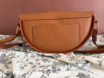 le sac est présenté de dos. il dispose d'une poche plaquée en cuir de la même couleur que le sac. les piqures sont beige