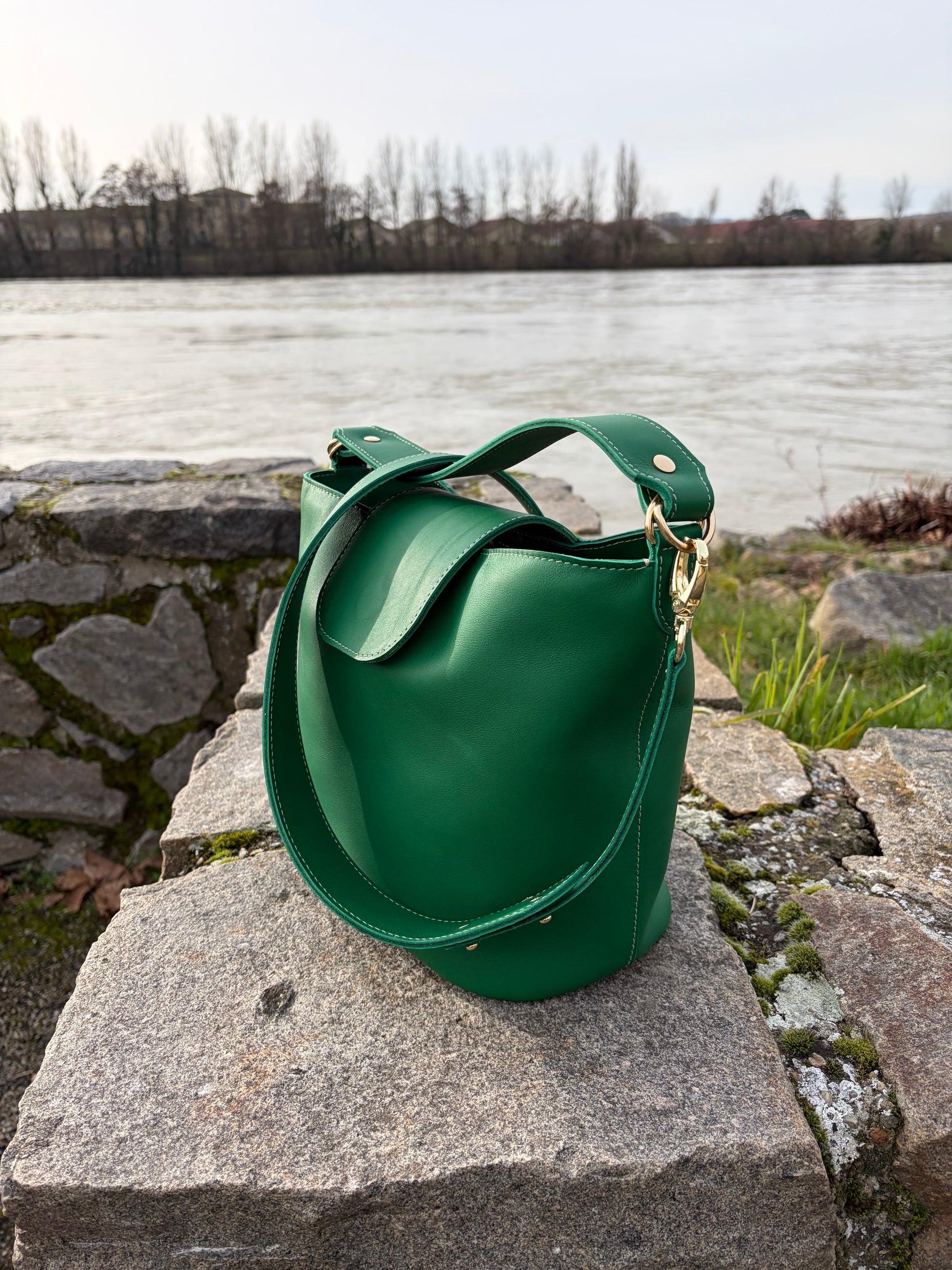 photo du sac seau garance vert posé sur un muret en pierre avec le Rhône en arrière plan 