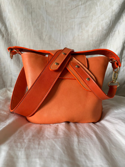 photo du sac seau garance en cuir au tannage végétal orange posé sur un drap en coton beige. 