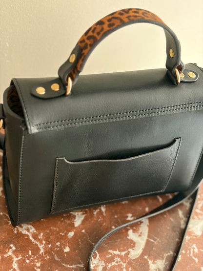 le sac est présenté de dos sur une table avec un dessus en marbre rouge