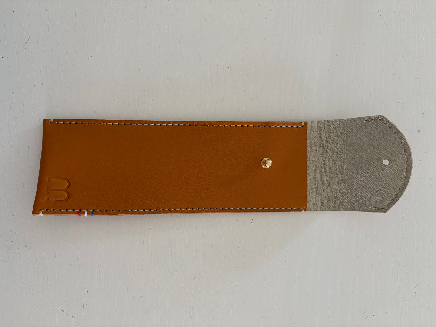 un étui en cuir marron doublé de cuir argenté est présenté ouvert. 