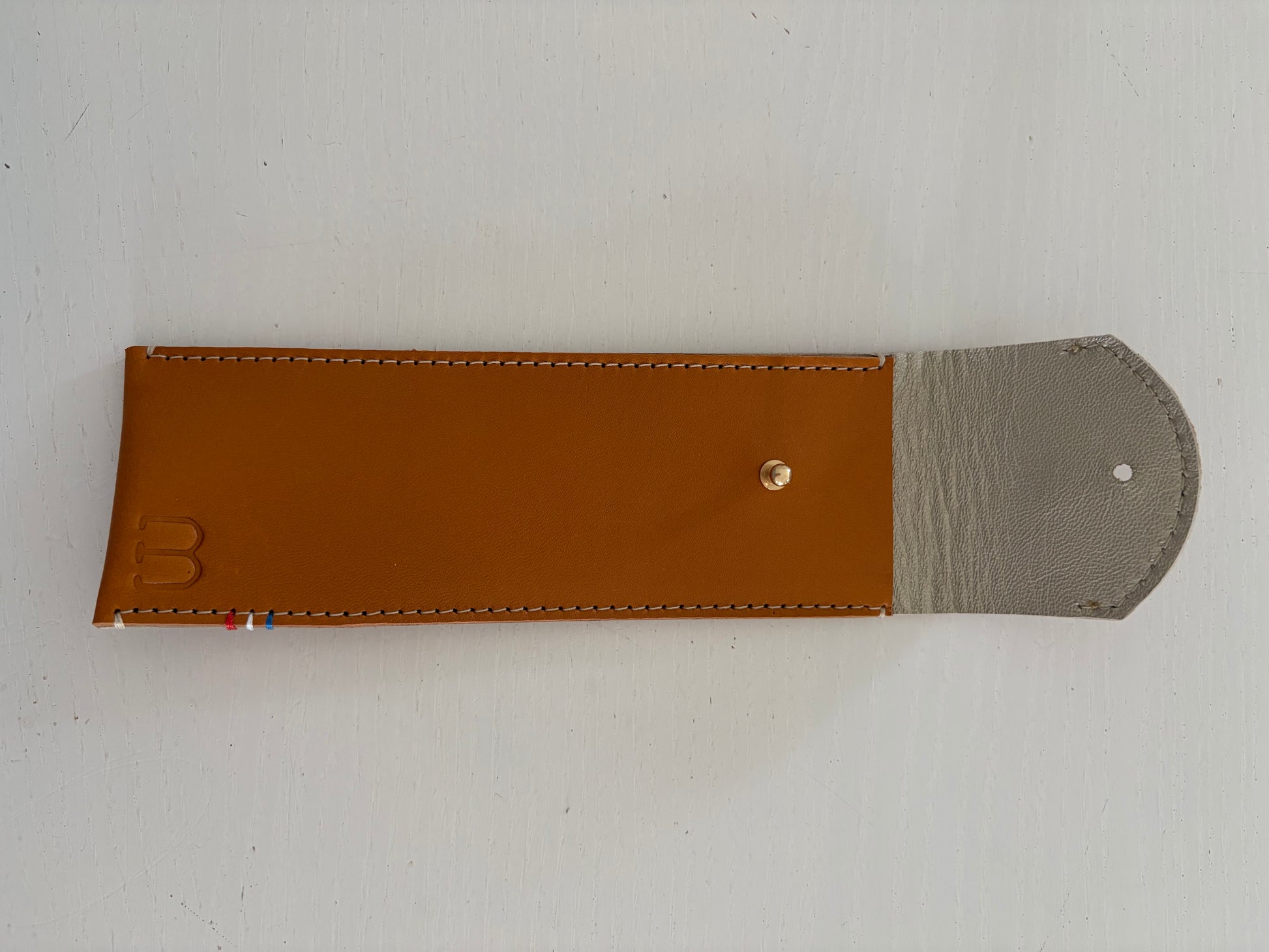 un étui en cuir marron doublé de cuir argenté est présenté ouvert. 