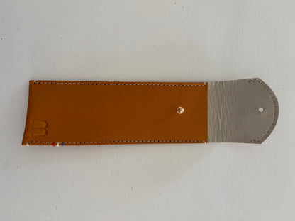 un étui en cuir marron doublé de cuir argenté est présenté ouvert. 
