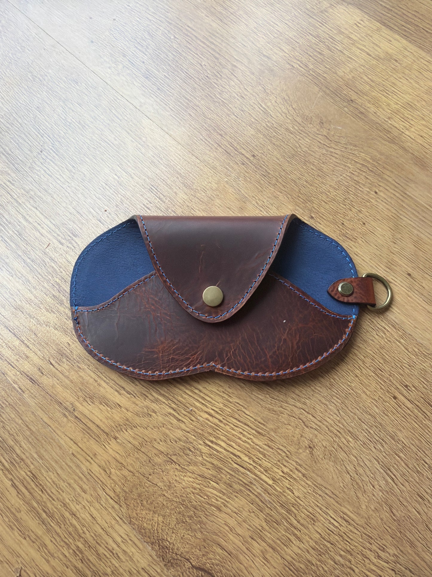 étui à lunette marron et bleu sur un sol en parquet