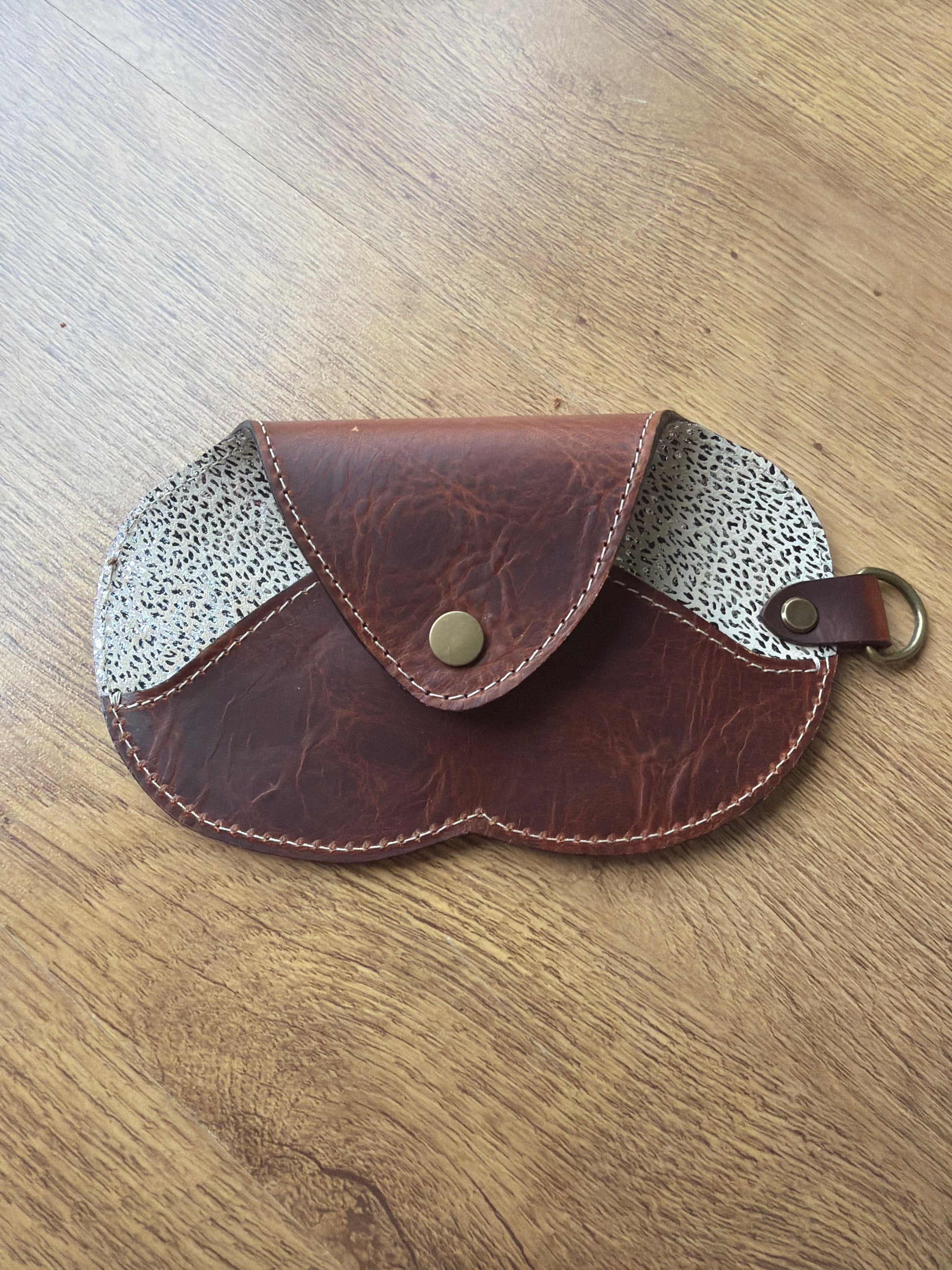 étui à lunette marron et cuir fantaisie sur un sol en parquet