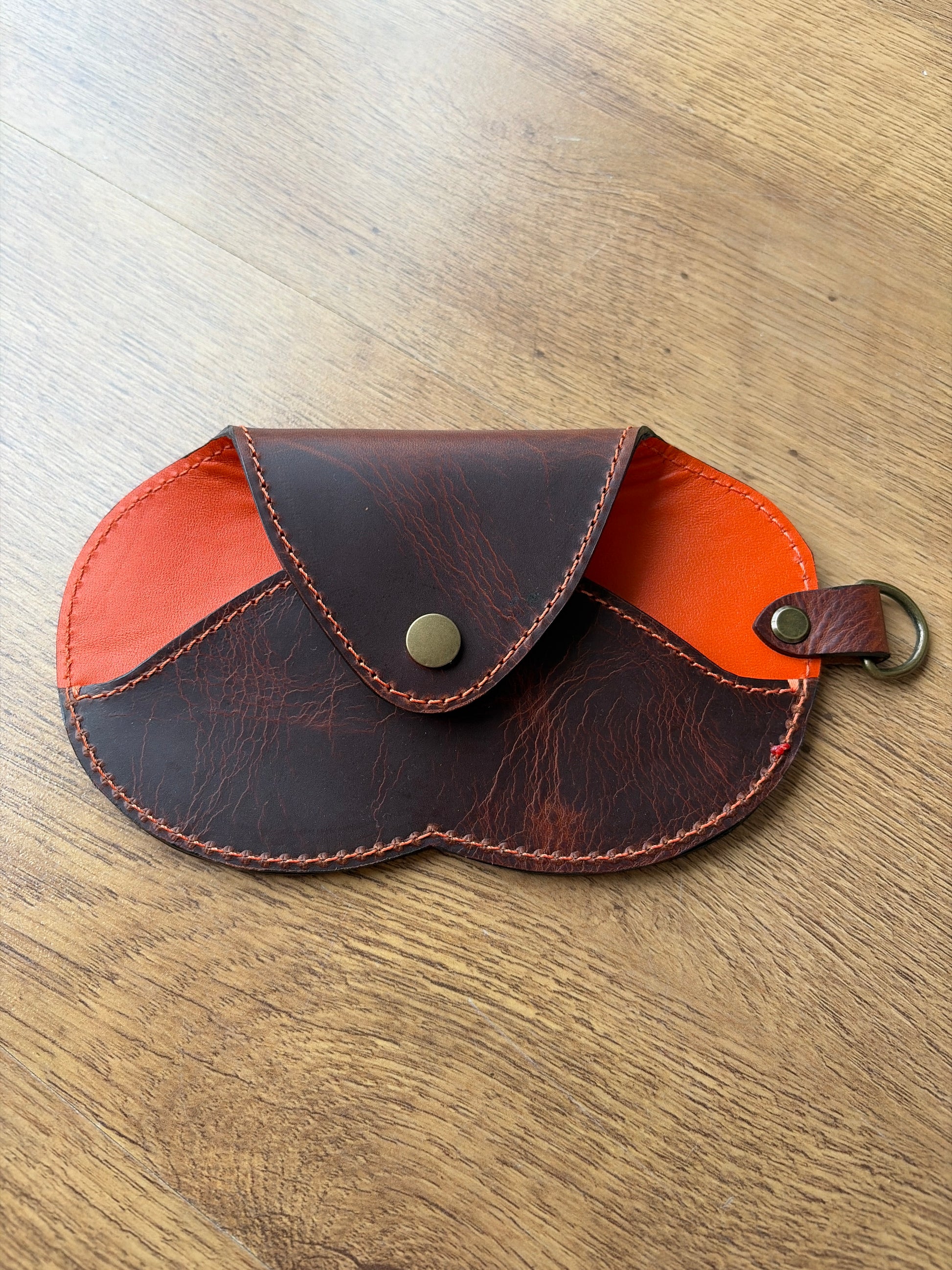 étui à lunette marron et orange sur un sol parquet bois